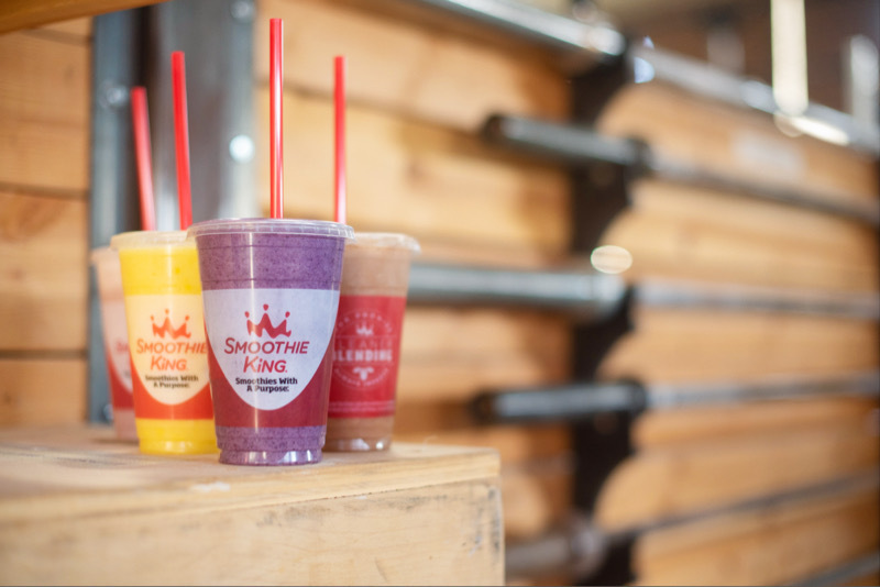 Three Smoothie King smoothies in front of a rack of barbells