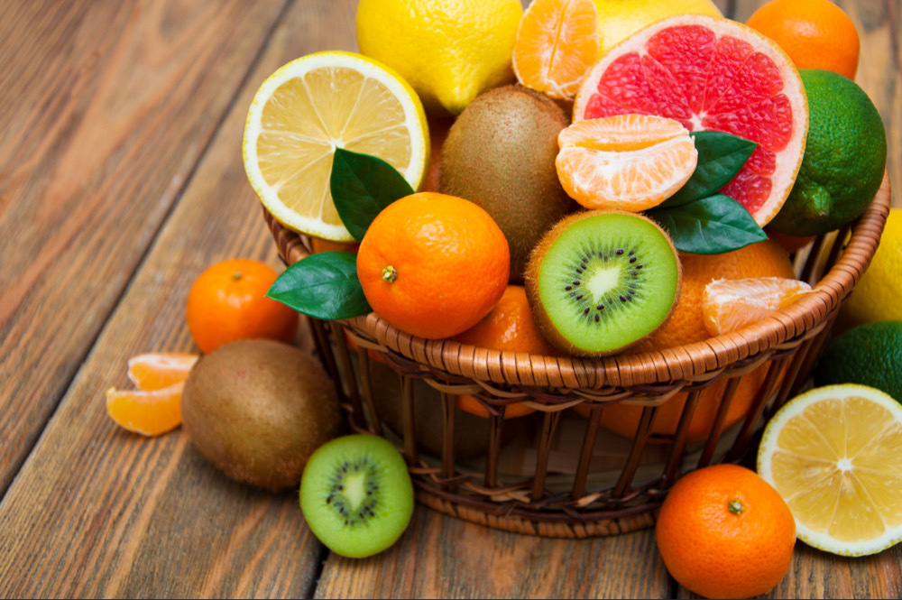 A basket of fruit, including kiwis, lemons, oranges, grapefruit, and a lime