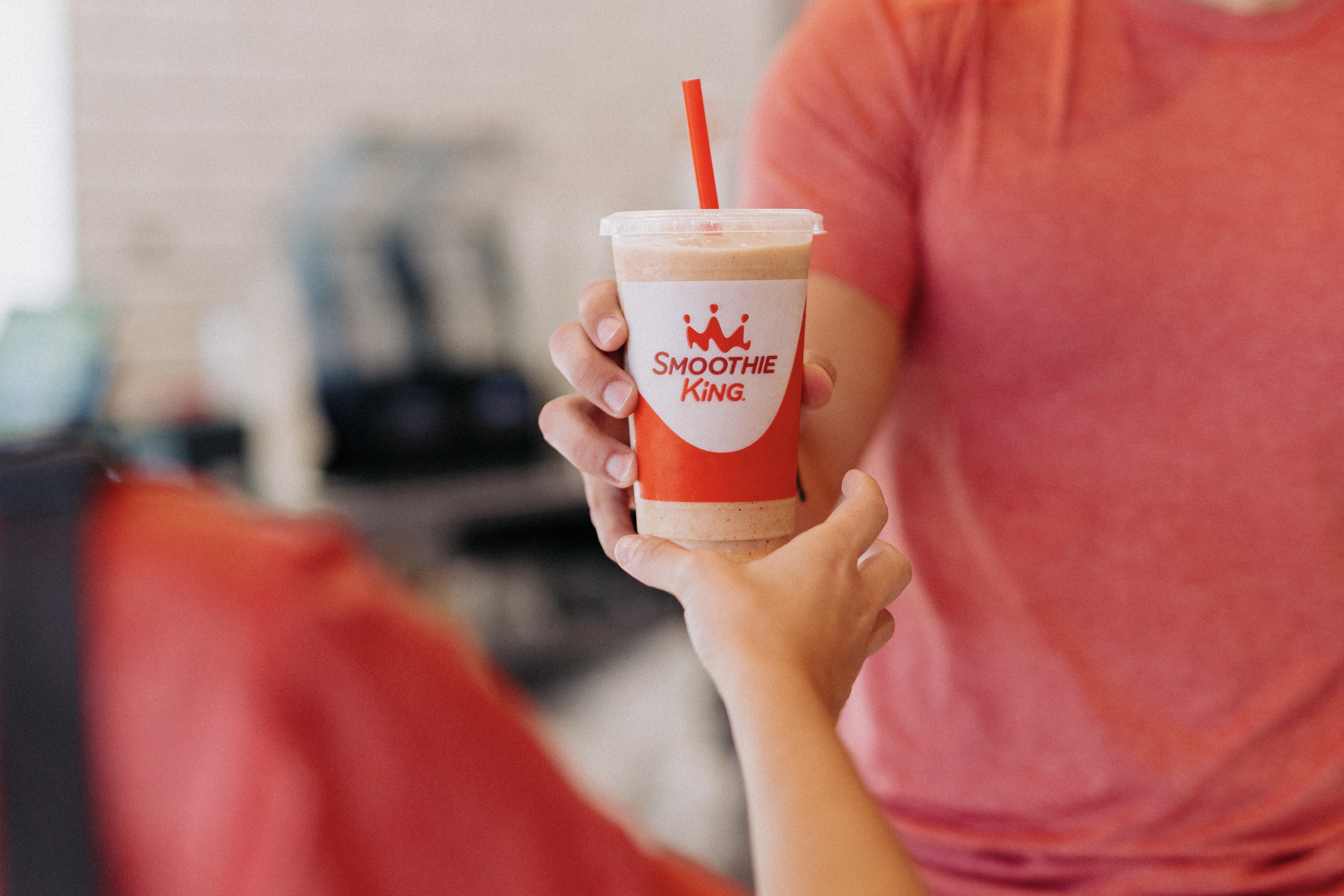 Smoothie King employee handing customer a pumpkin smoothie