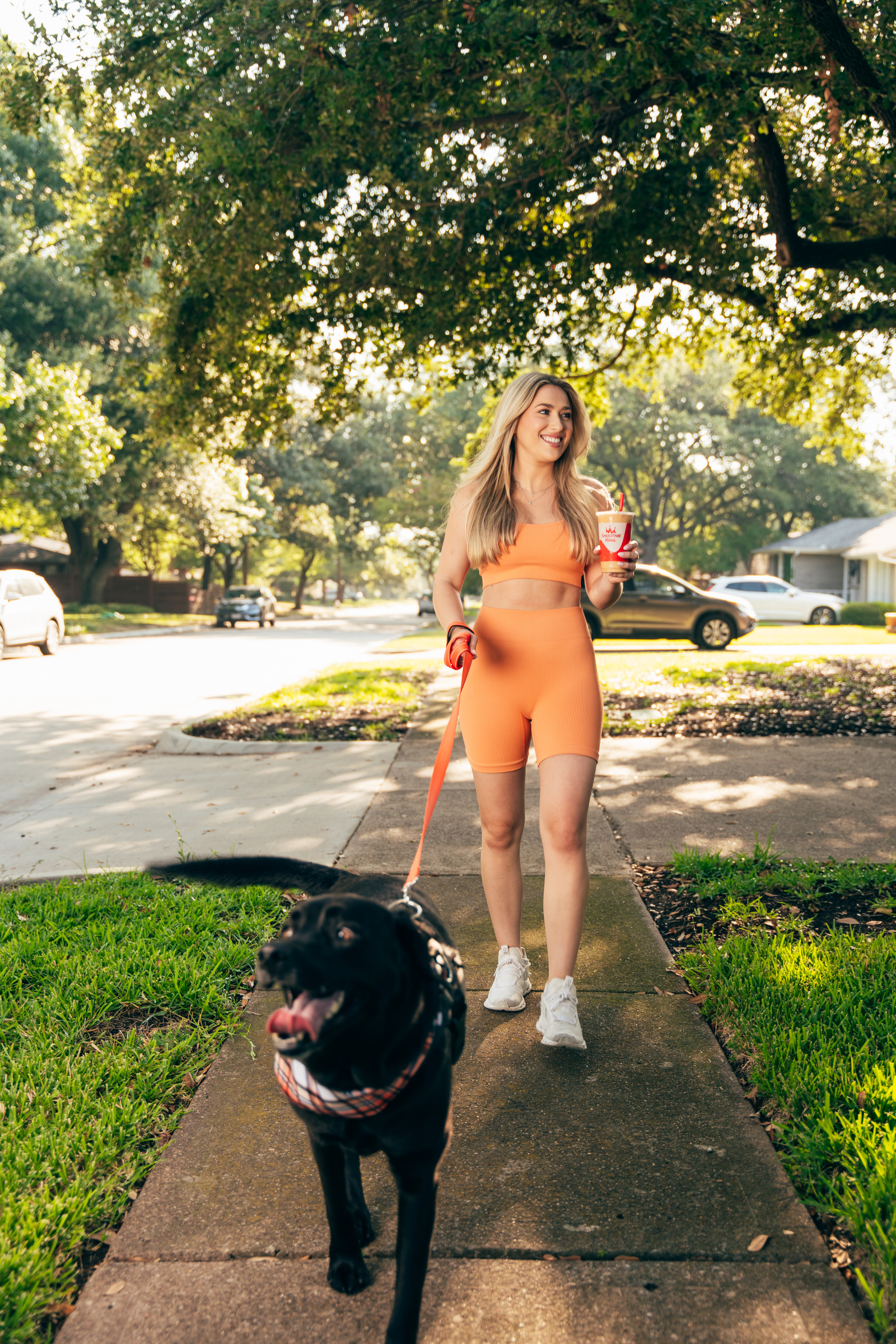 Woman walking her dog while drinking a GLP-1 smoothie