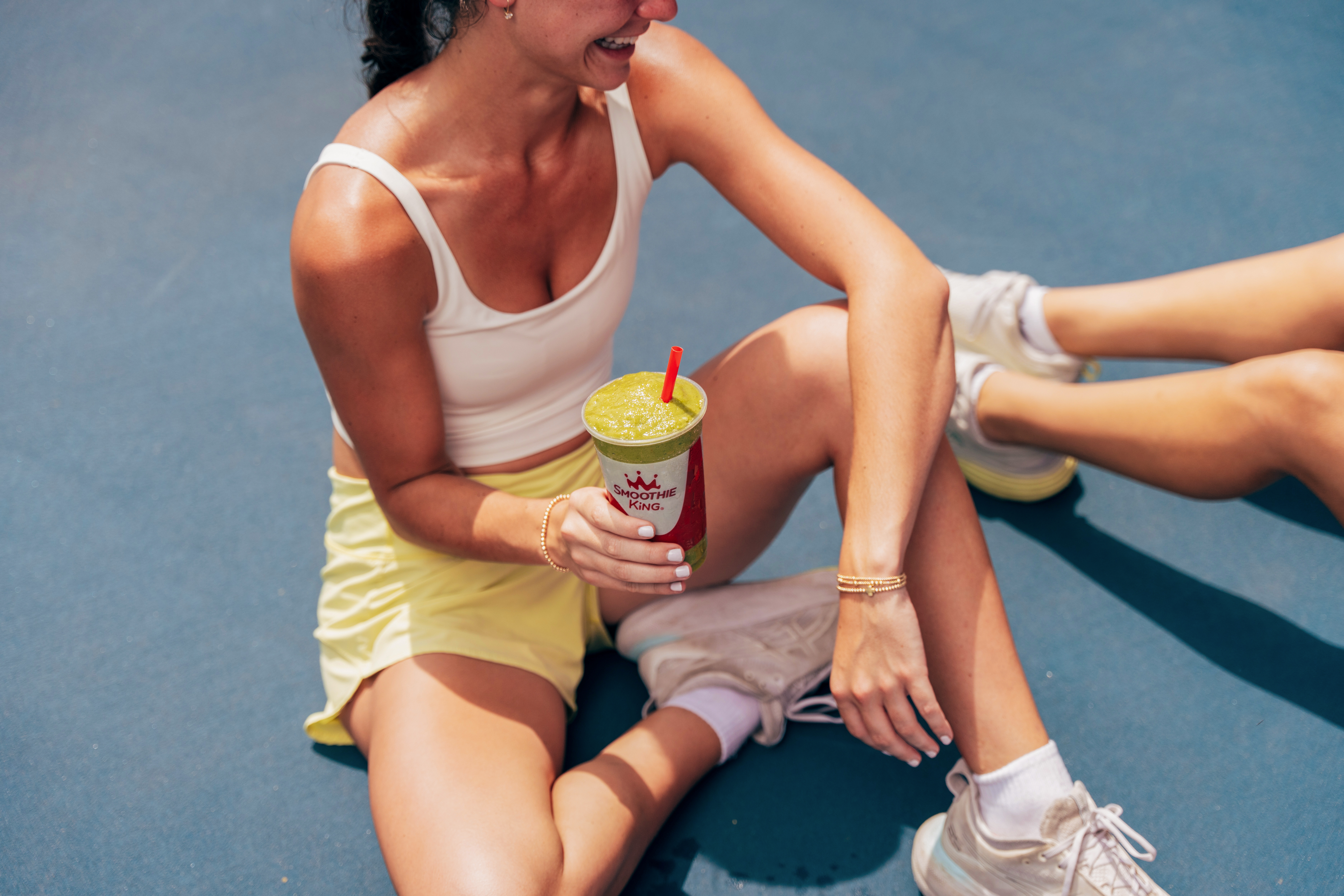 A woman drinking a smoothie after her workout with a friend