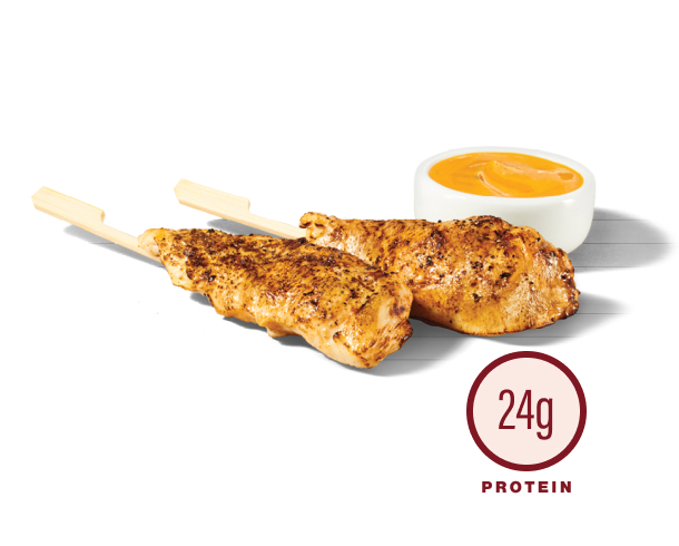 Two grilled chicken skewers beside a cup of dipping sauce - 24g protein