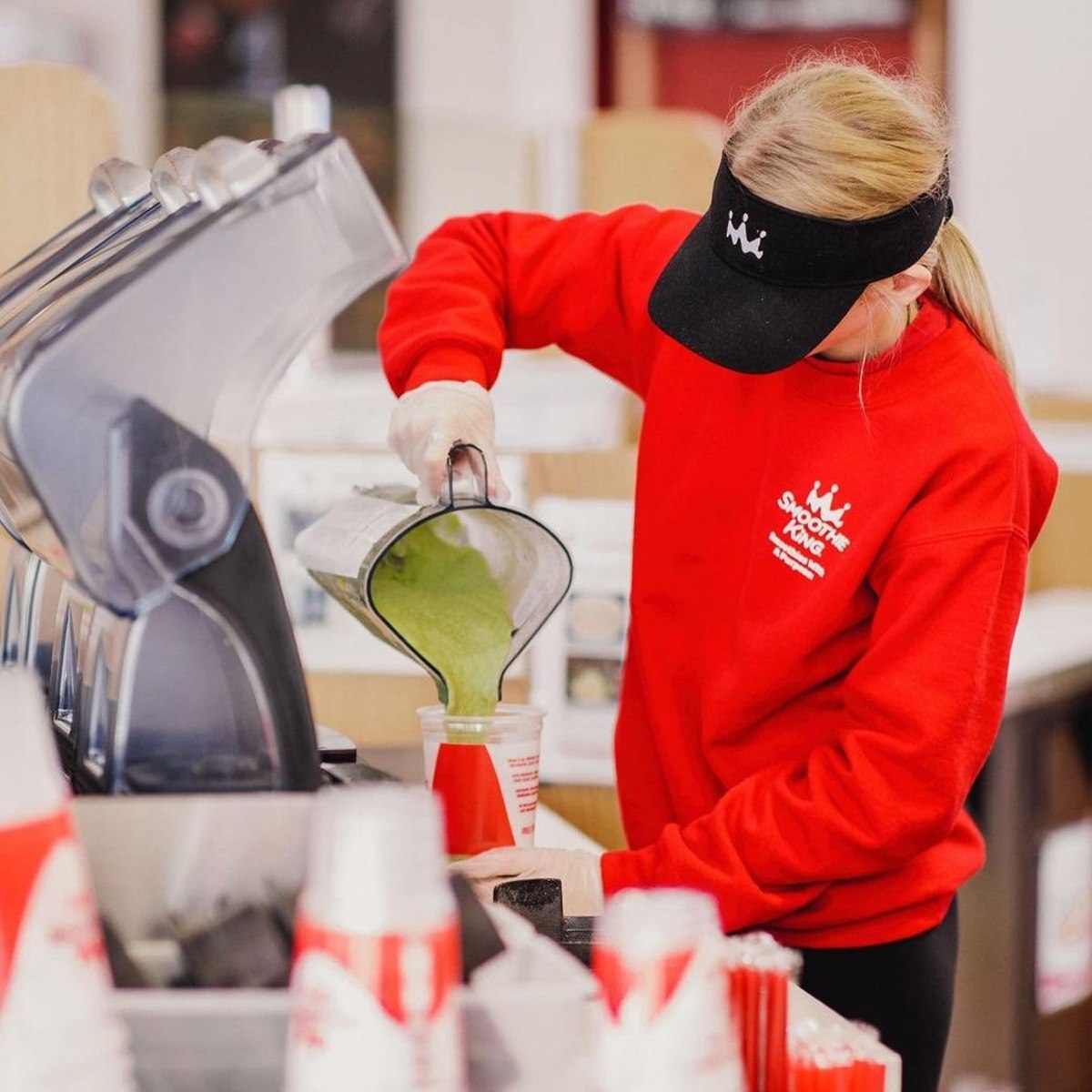 Smoothie King employee filling cup with a green smoothie