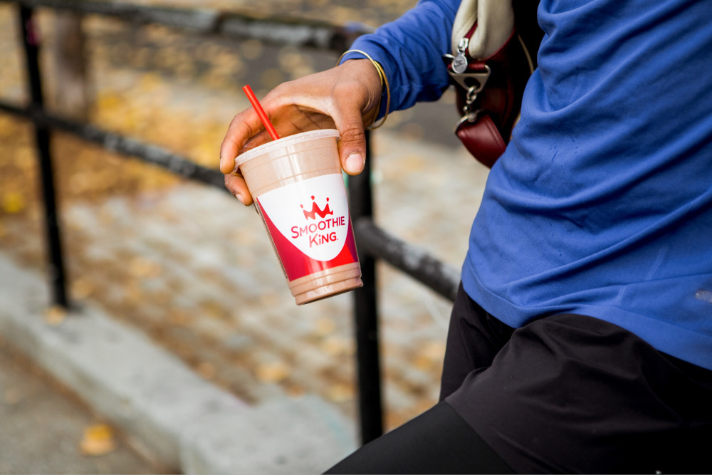 Hand holds an espresso smoothie from Smoothie King outside in Autumn